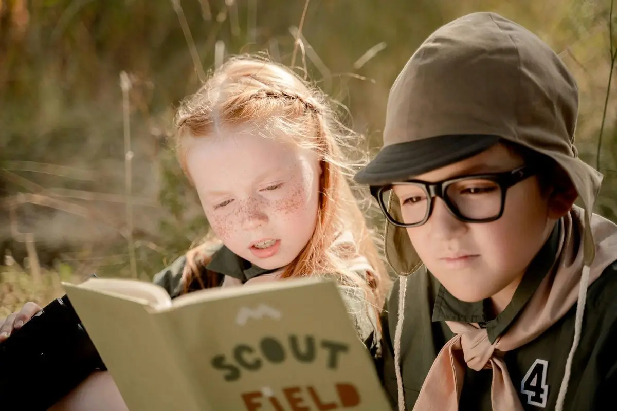 Two girl scouts' scout reading scout field guide.