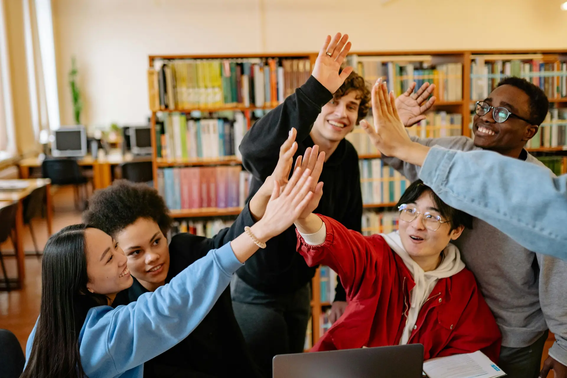 Bunch of people high fiving in a library.