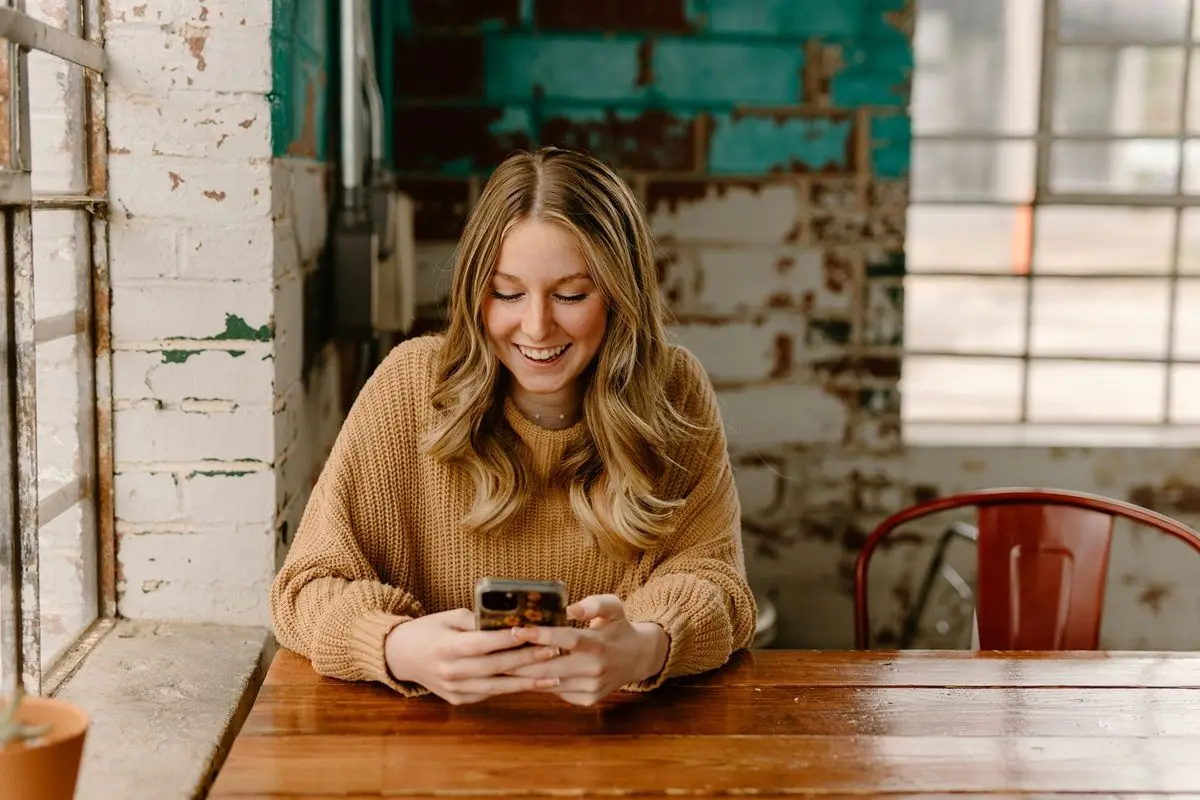 A person laughing while checking their phone.