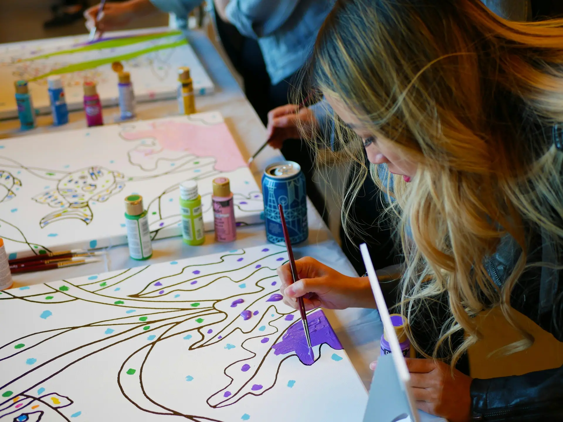 People drawing on paper with brushes in a painting party.