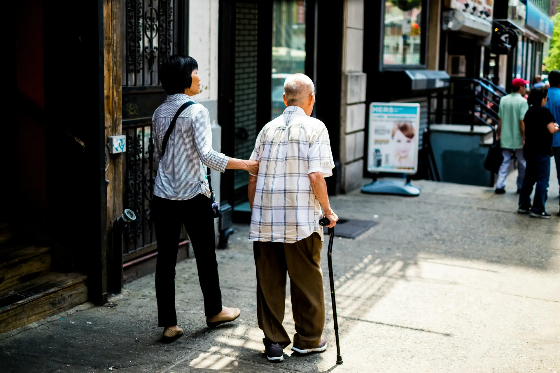 A young man helps an elderly person on the streets.