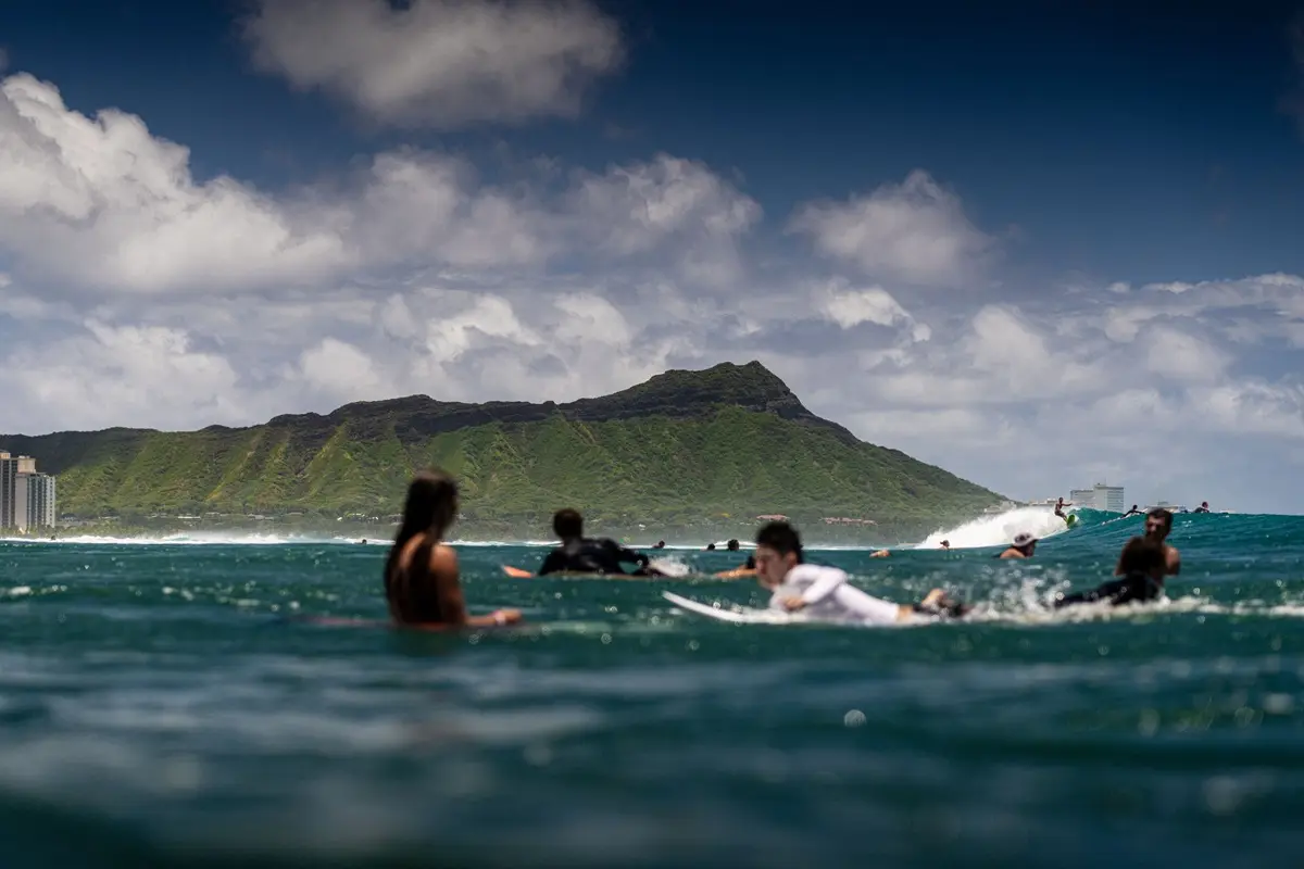 Surfers riding waves with Diamond Head in the background, a classic Hawaiian seascape.