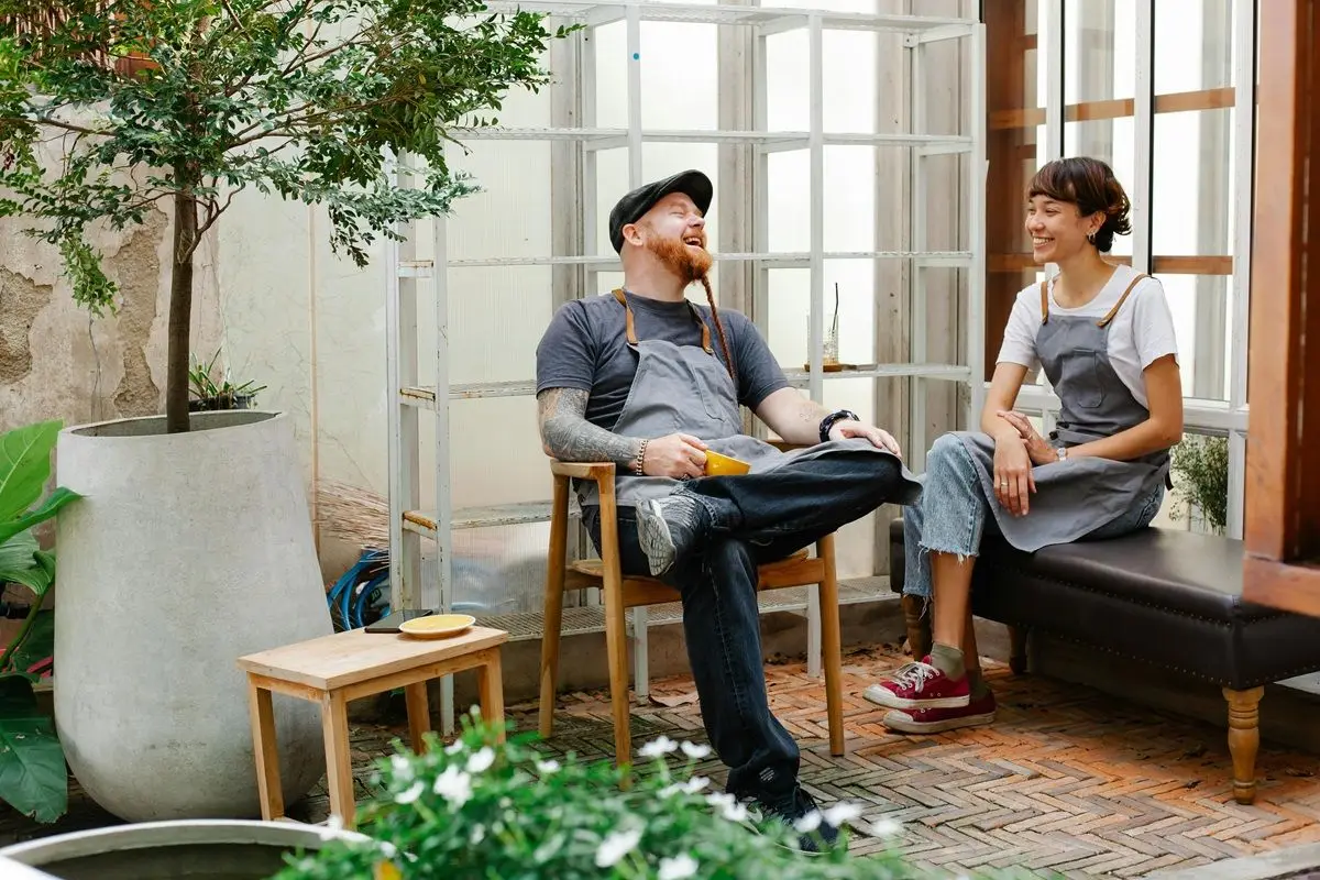 A couple sitting on the patio and laughing and talking, possibly one complimented the other. 