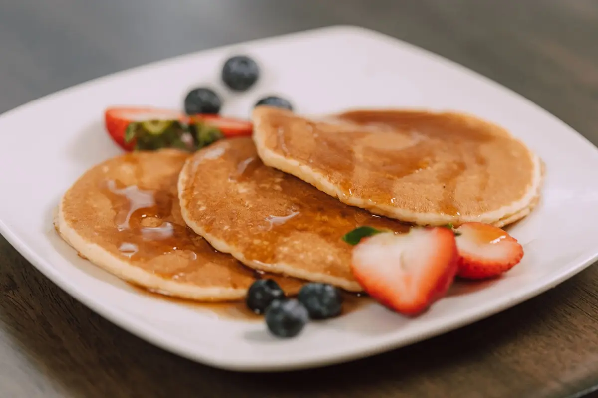 Mouth-watering pancakes topped with syrup and fresh berries, perfect for a wholesome breakfast.