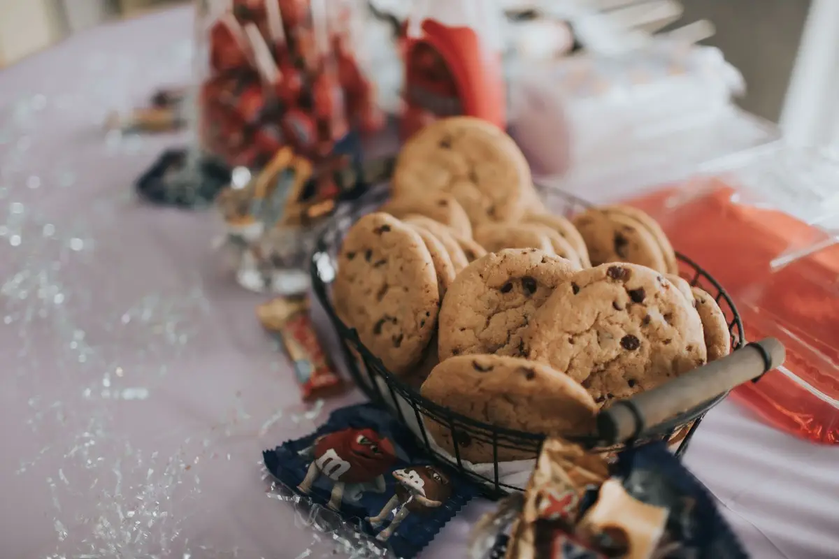 Basket of homemade chocolate chip cookies with candy on a festive table.