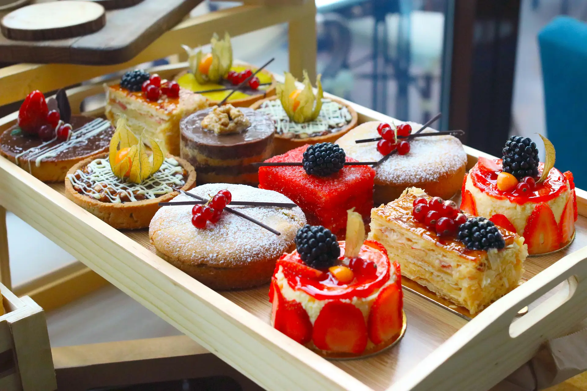 An assortment of different flavours of cakes placed on a wooden tray.
