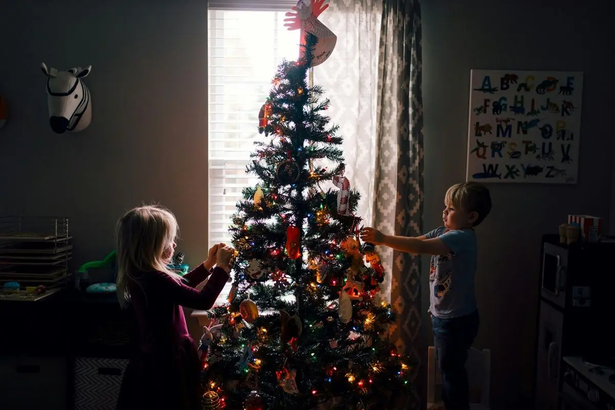 Two kids decorating their Christmas tree.