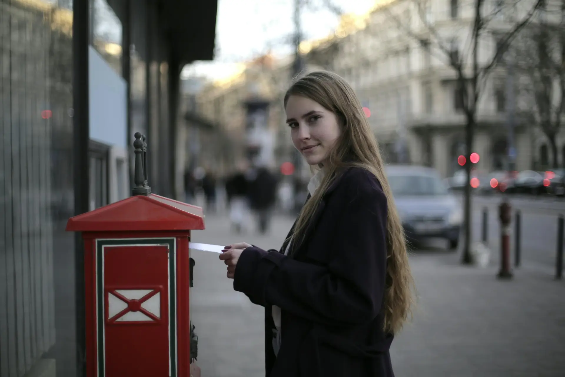 Woman posting a letter in a red post box.