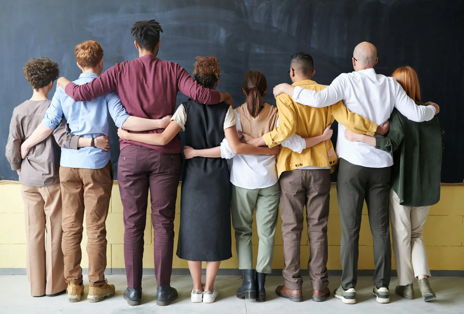 A group of people hugging each other while facing the board.