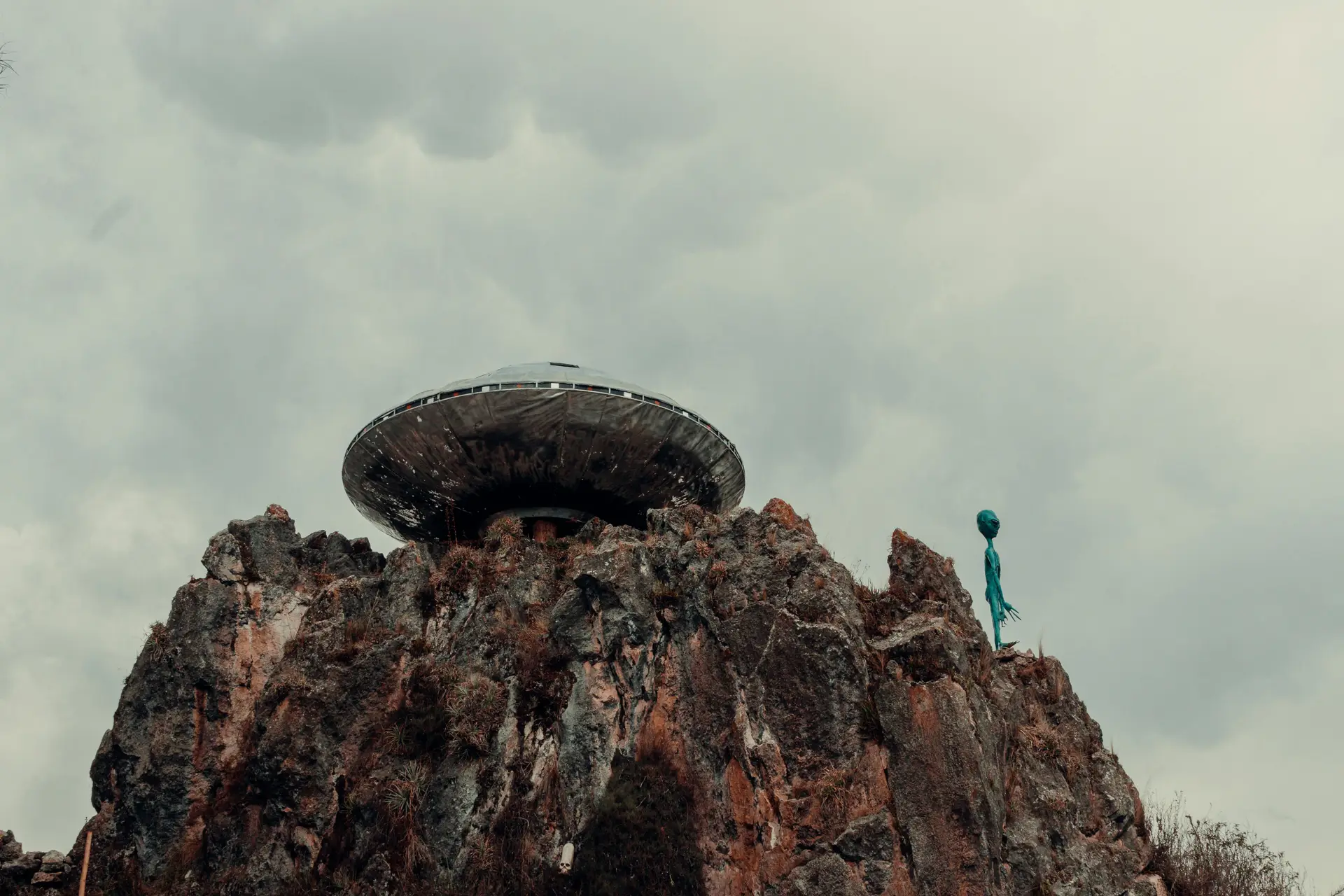 UFO and an alien on a rock formation.