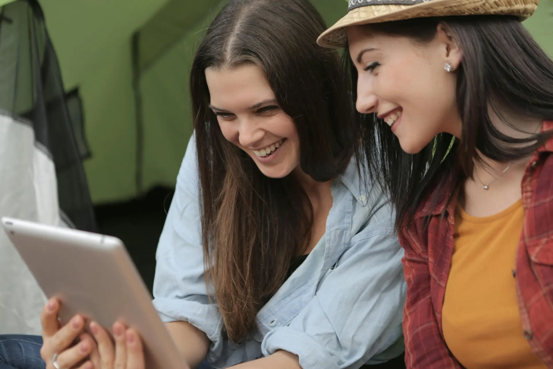 Two women looking at their tablet while laughing.