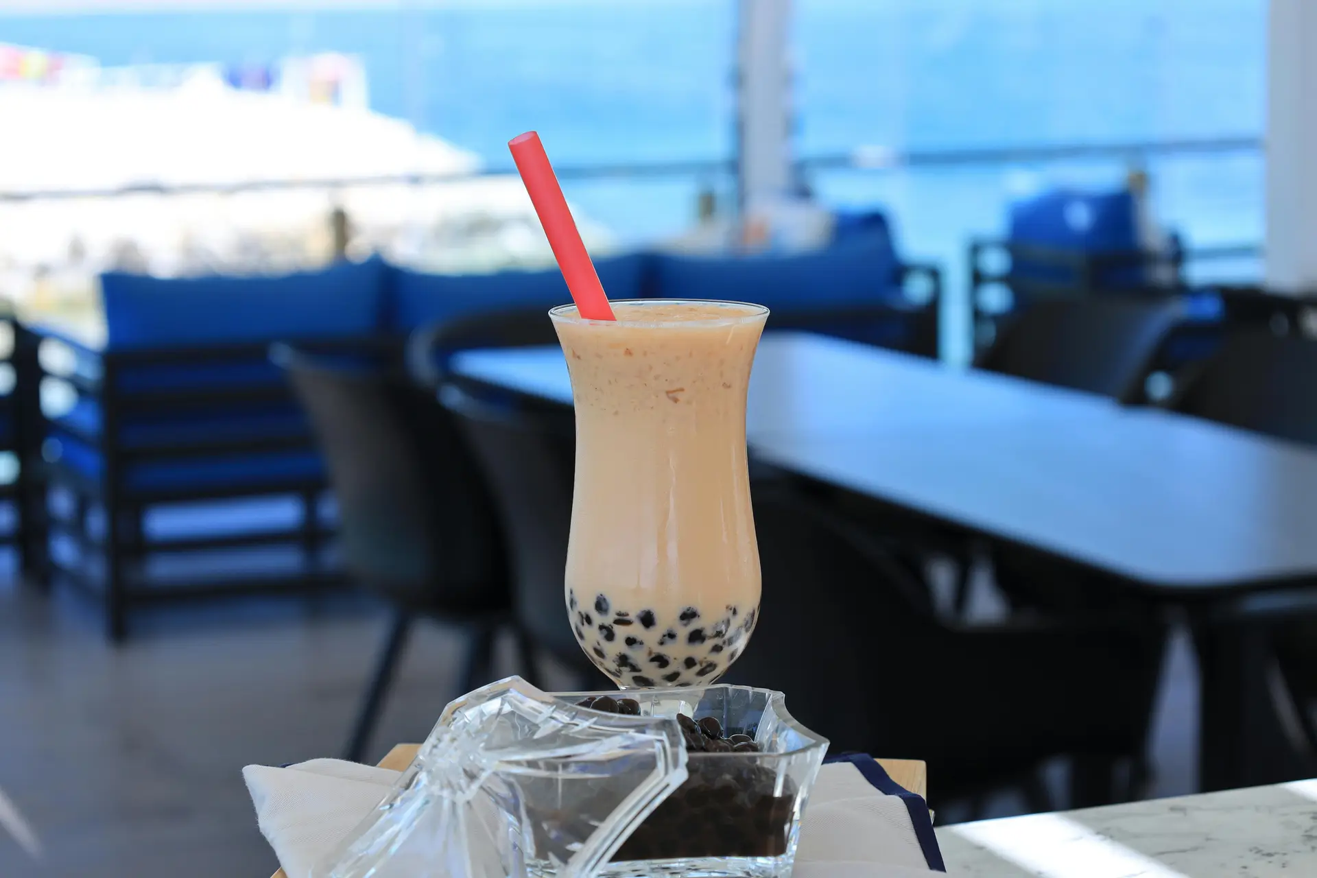A glass filled with boba tea and has a red straw in it.