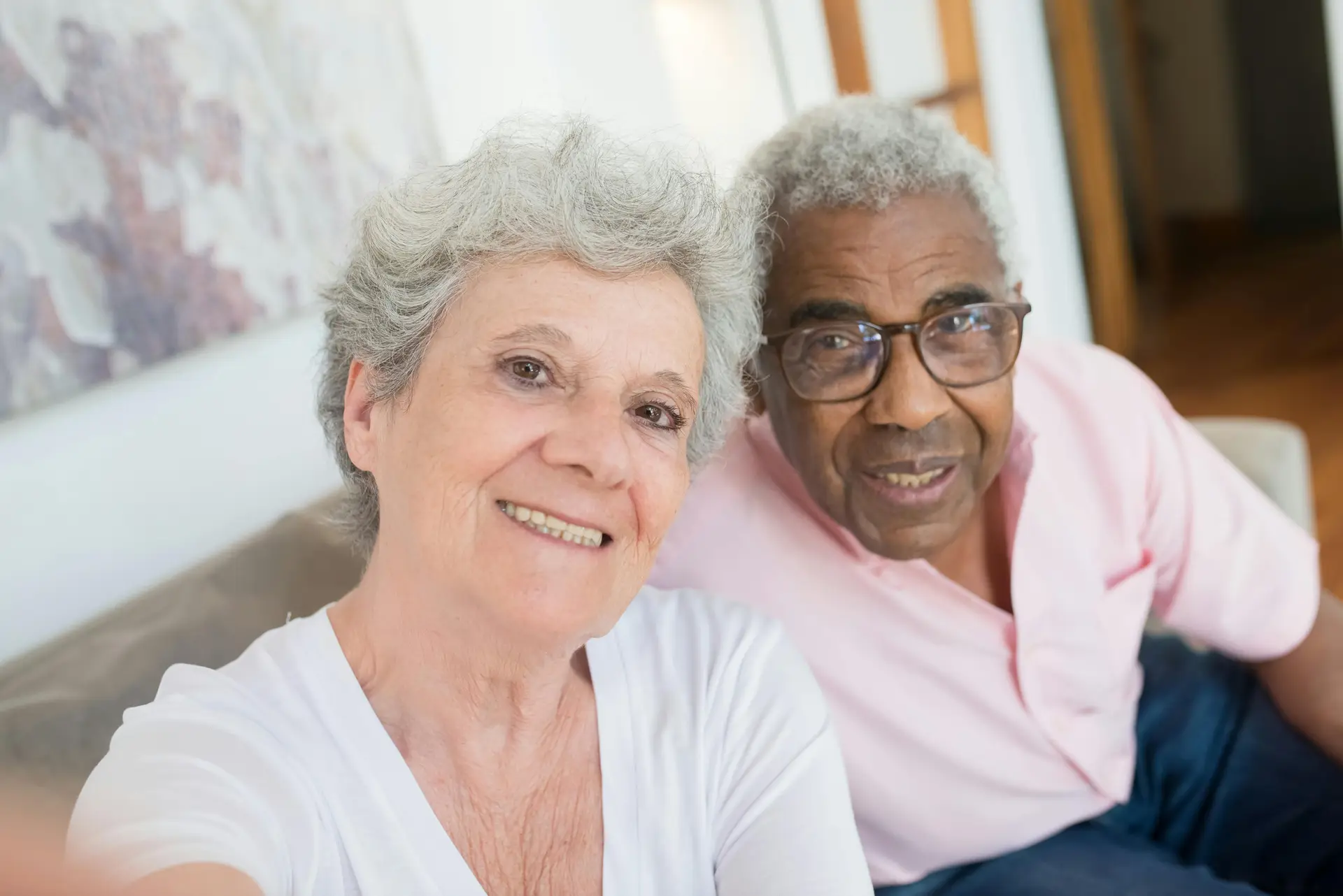 Aged woman in white shirt sitting beside a man of same age.