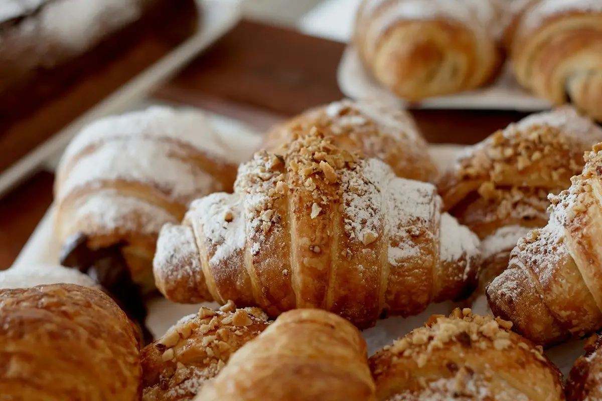 A pile of croissants with powdered sugar on them.