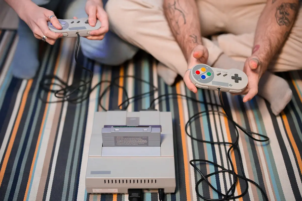 Two people playing a vintage gaming console, showcasing retro entertainment.