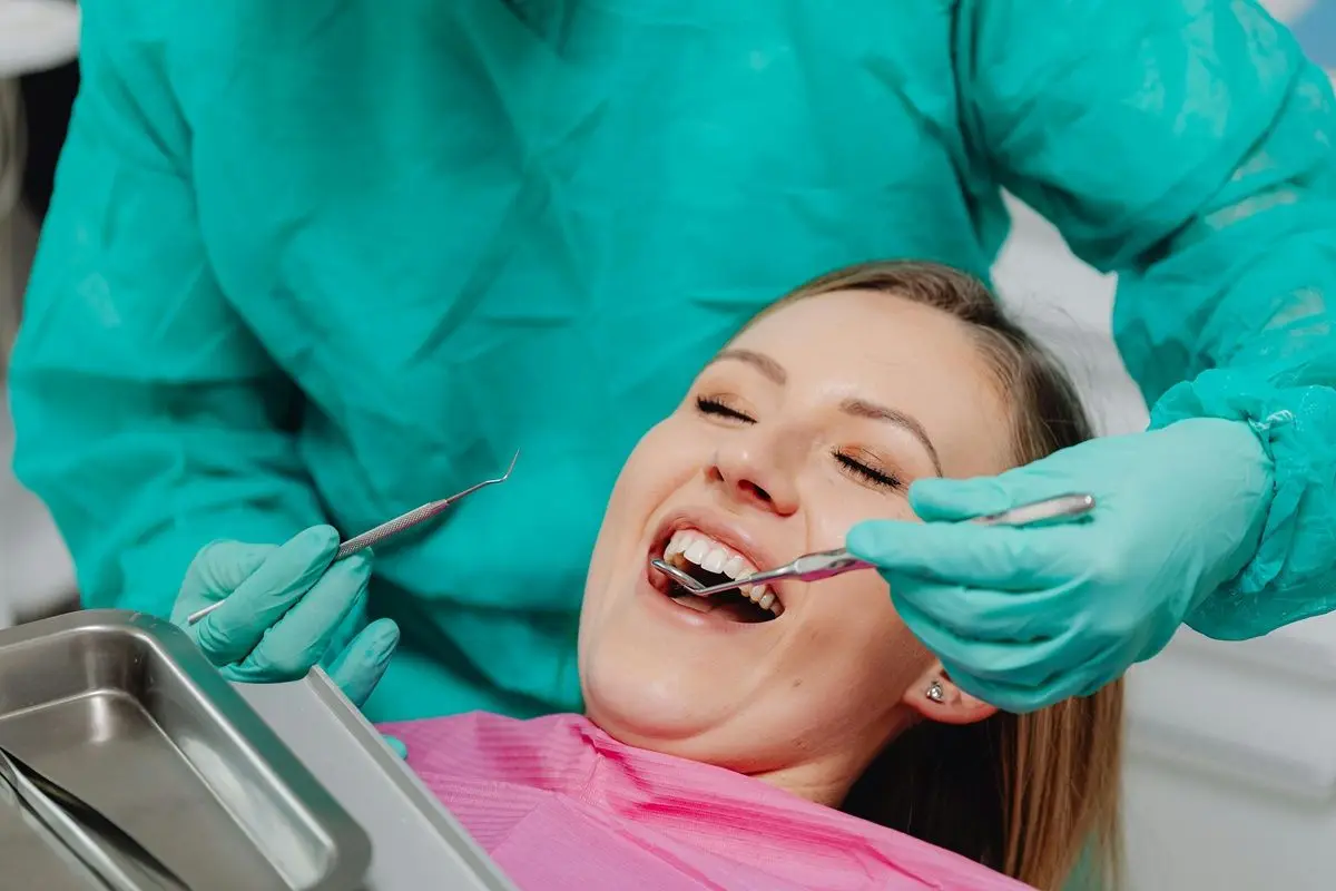 A patient smiling while being operated by a dentist in a dental chamber.