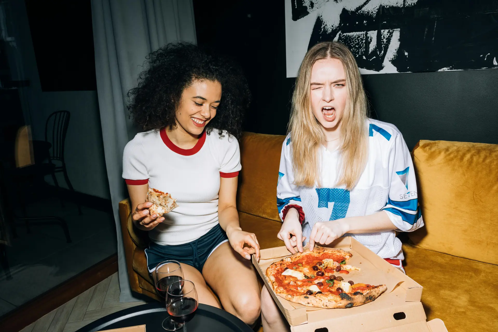 Two girls having a pizza party indoors.