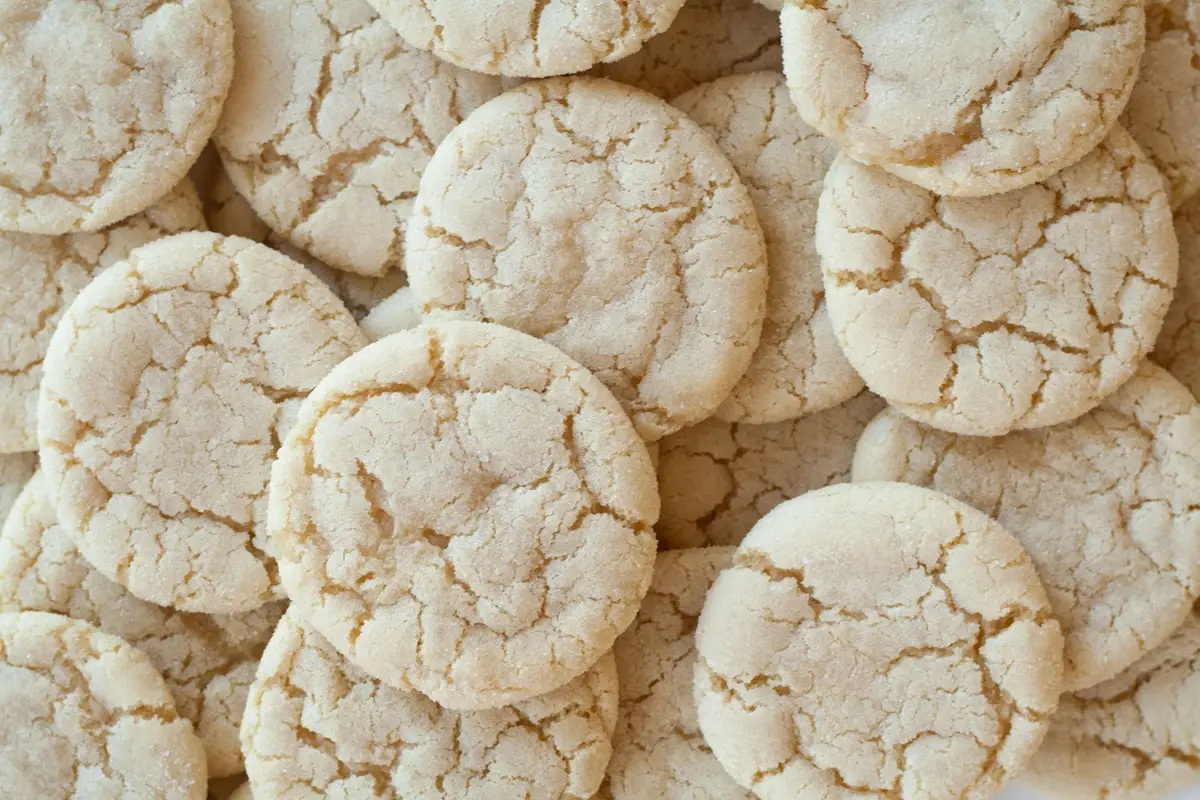 A close-up shot of homemade sugar cookies with a cracked surface, showcasing their texture.