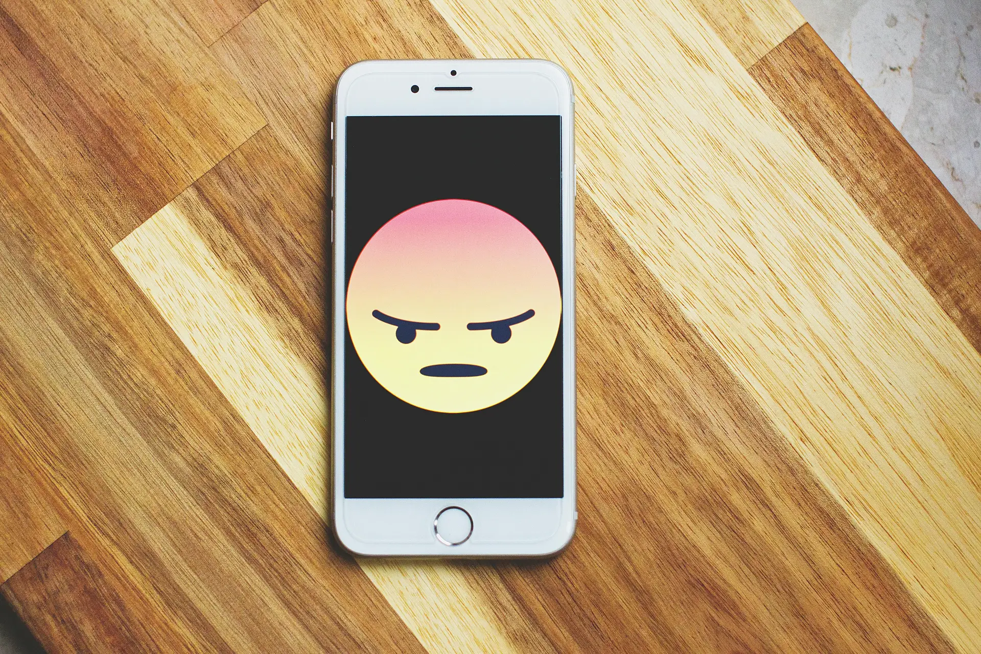 Angry emoji on a silver iPhone 6.