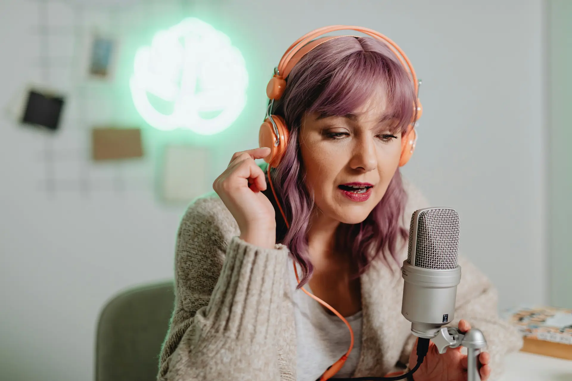 A woman podcaster talking on a micorphone while wearing a headphone.