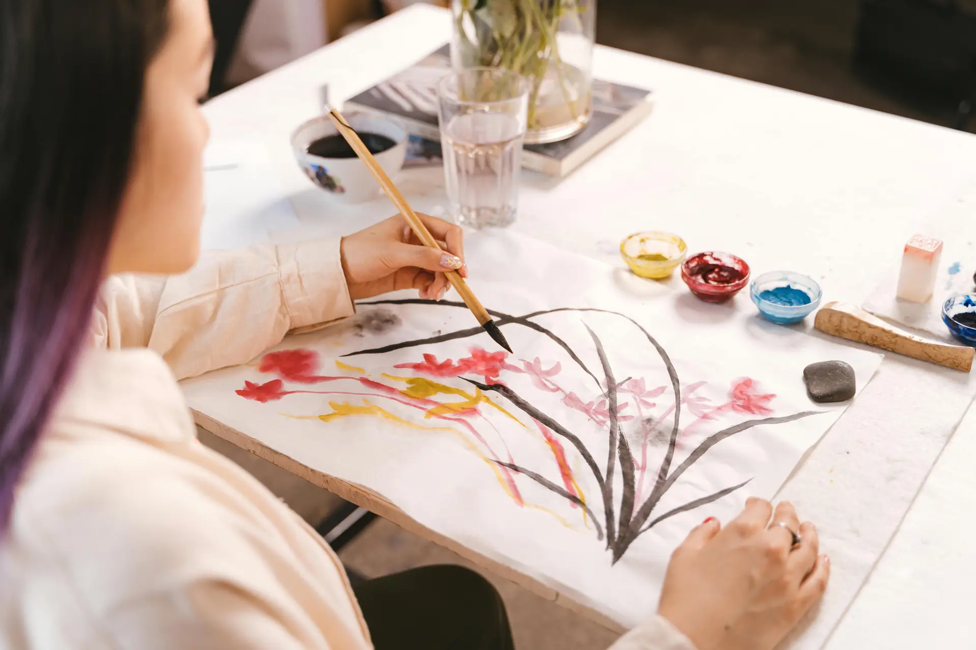 A woman holding a paint brush with her left hand while drawing.