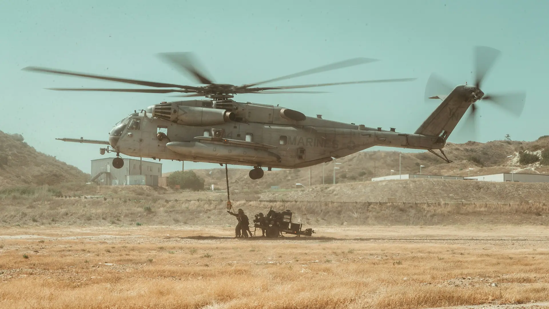 A gray helicopter on brown field during daytime.