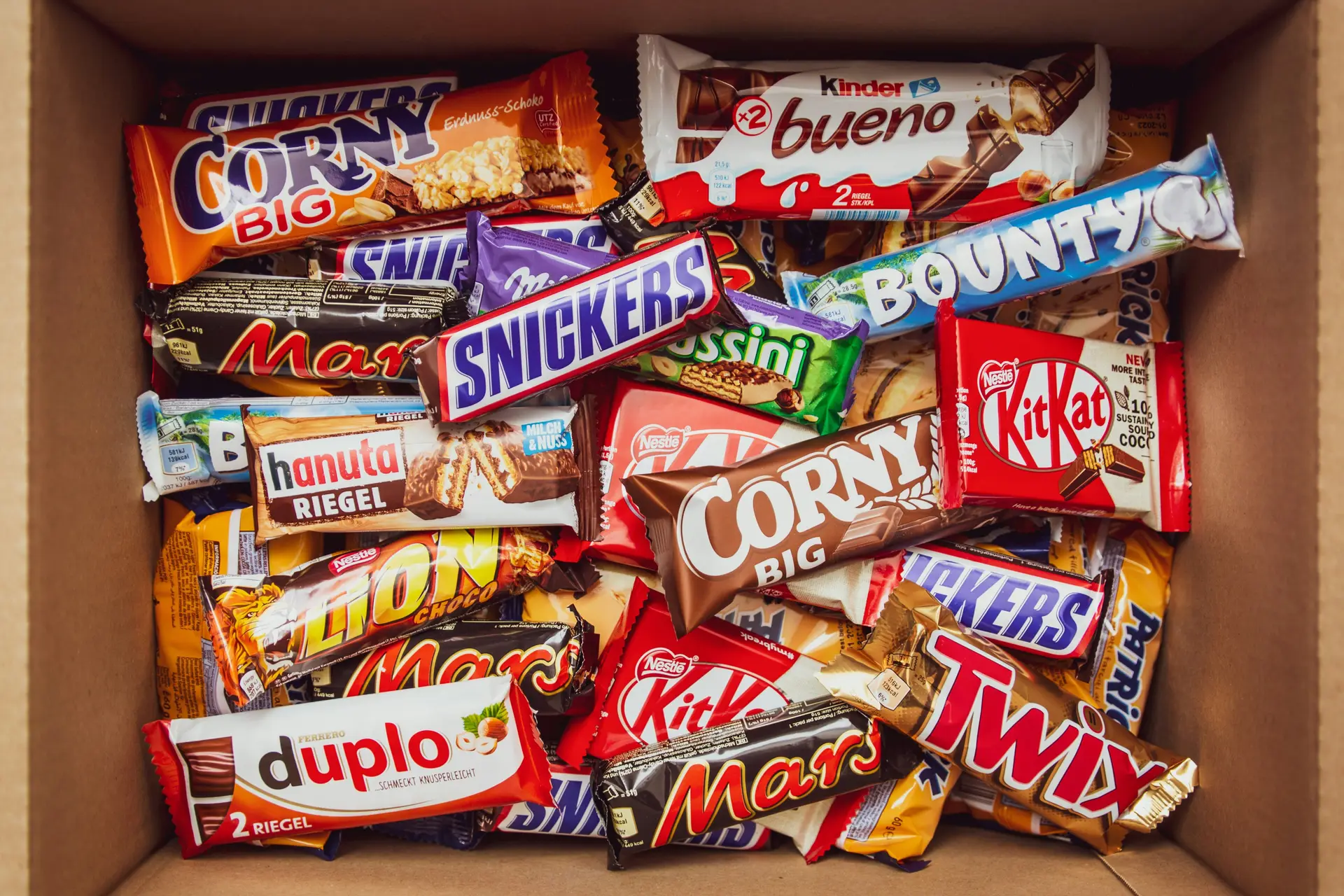 A bunch of chocolate bars from different comapny in a cardboard box.