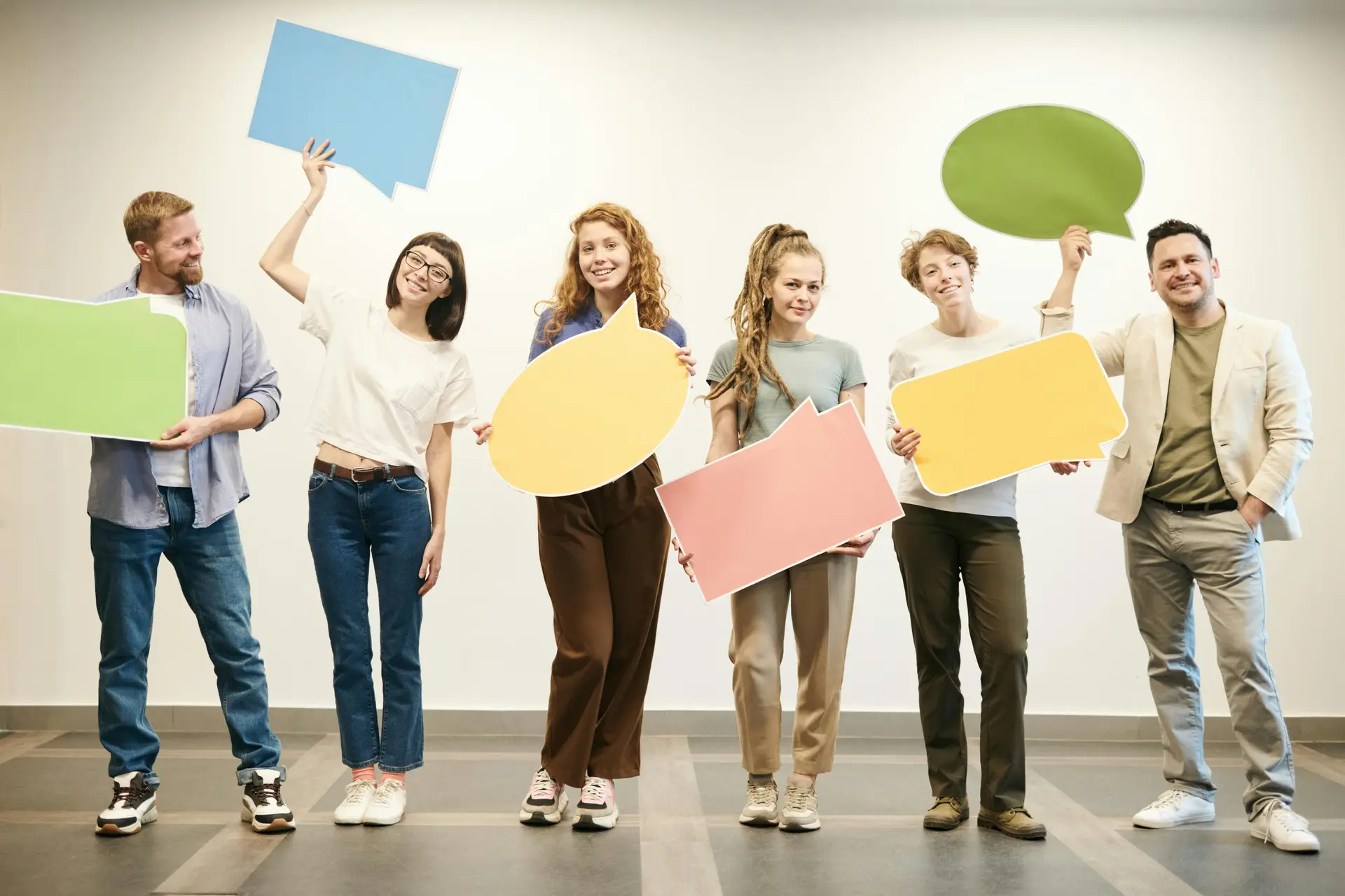 Group of men and women standing with chat bubble cutouts.