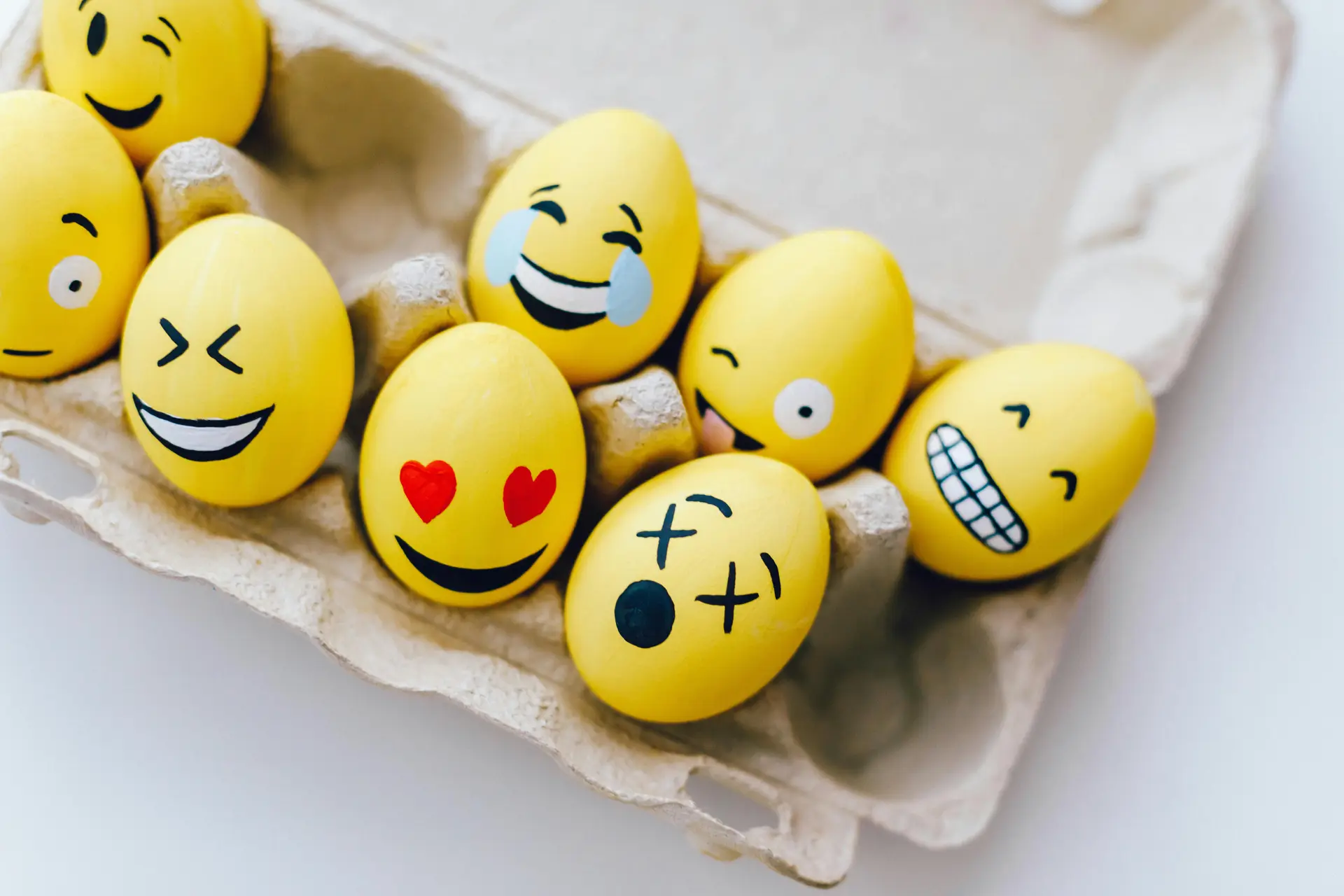 Yellow painted eggs with various emojis on emoji day,