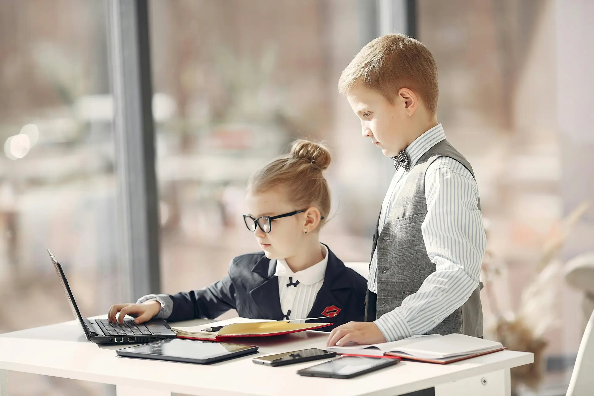 Cute business kids working on project together surfing laptop in light workplace.