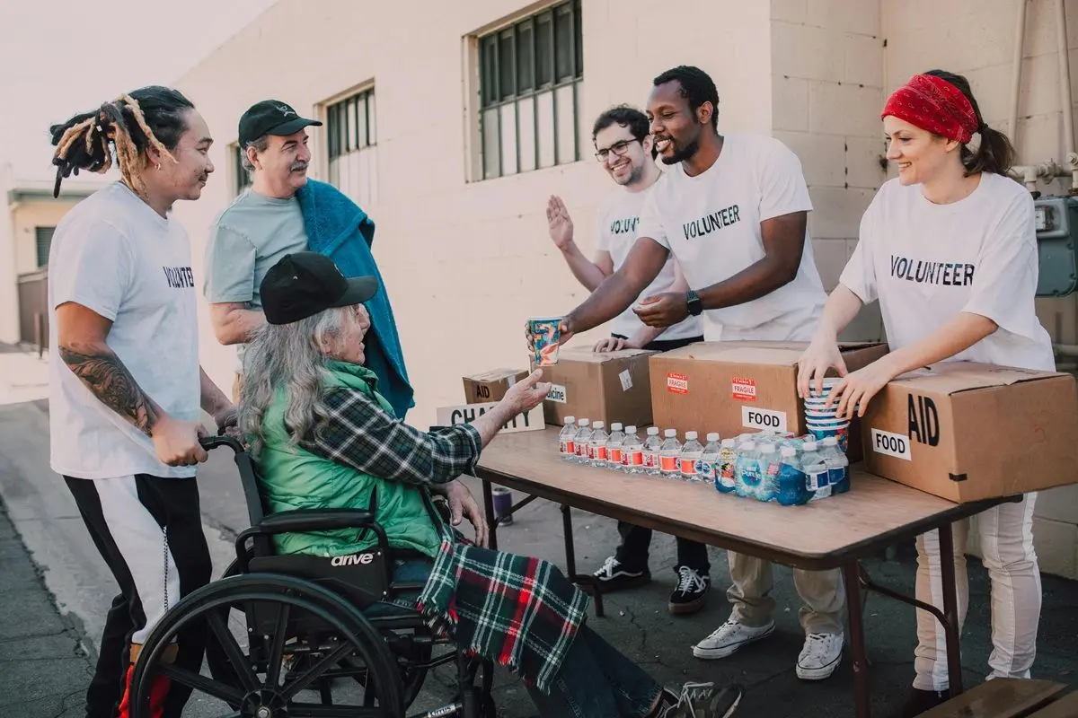 A group of voluneteers helping an eldernly person on a wheel chair.