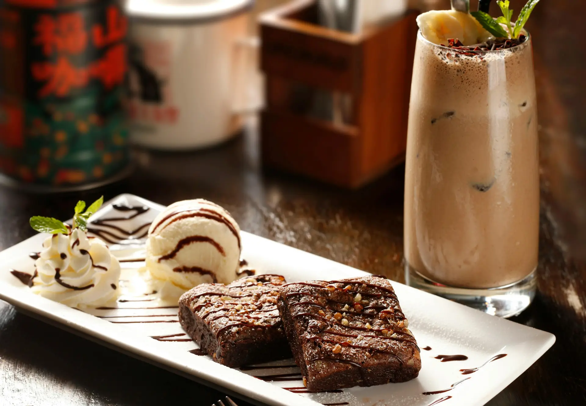 Vanilla ice cream served with brownie decorated with chocolate syrup and chocolate milkshake.