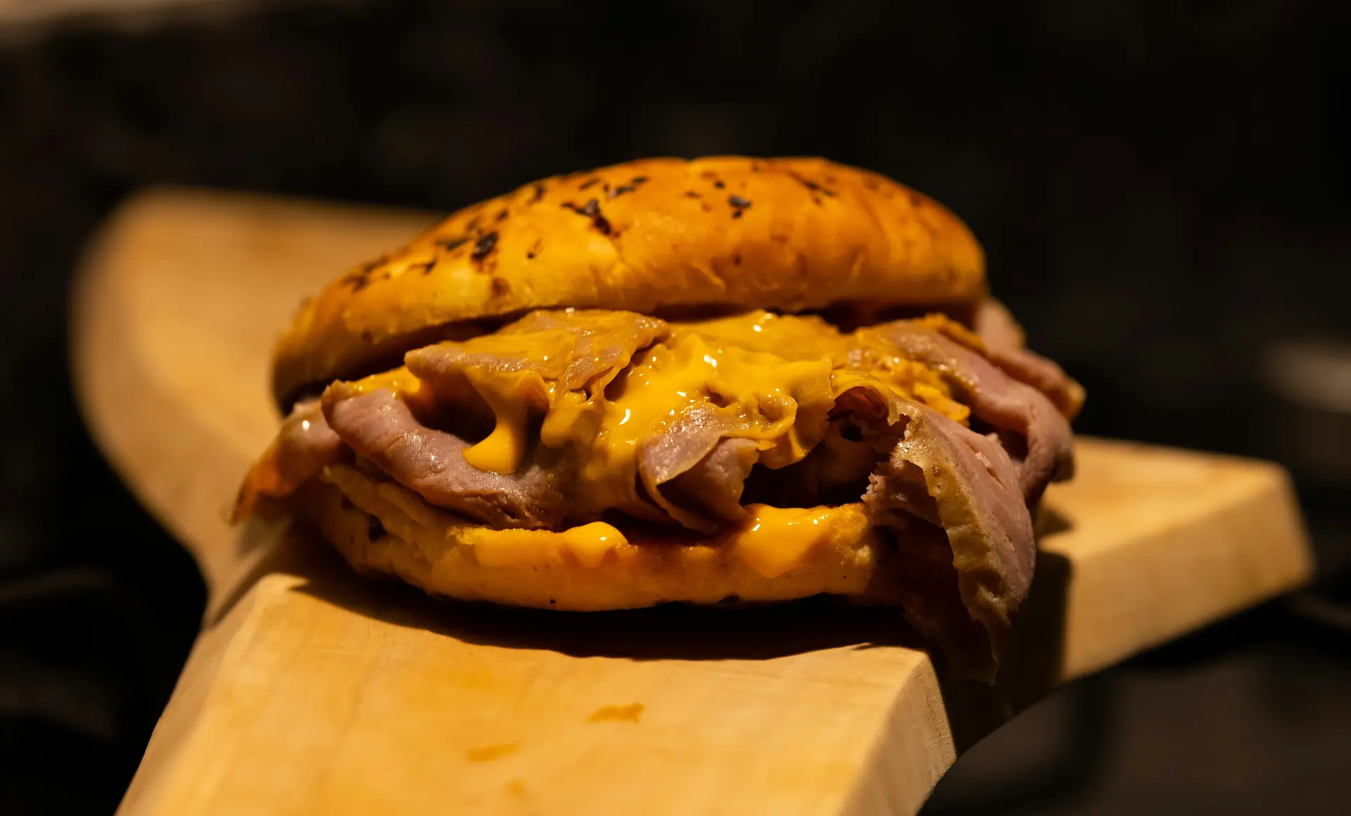 Cheesesteak sandwich with shredded meat and melted cheese viewed in focus.