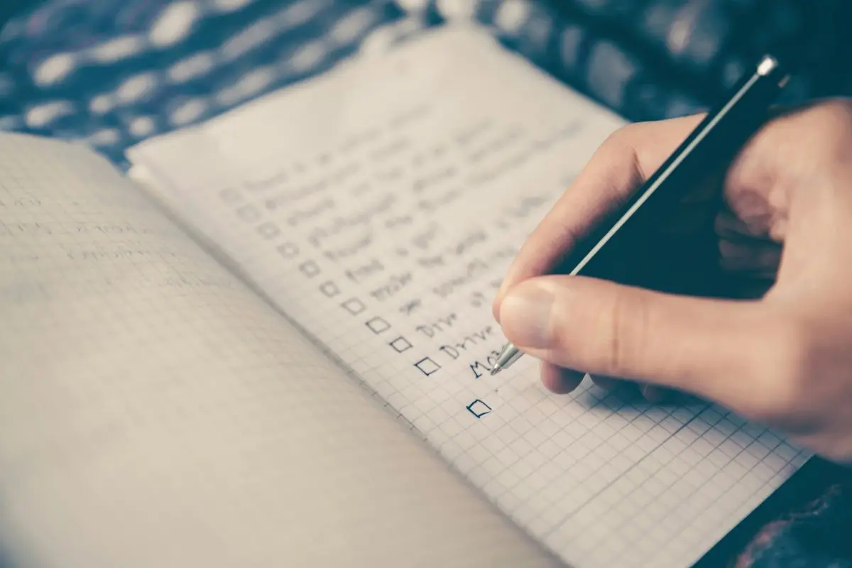 A person writing in a notepad with a black pen.