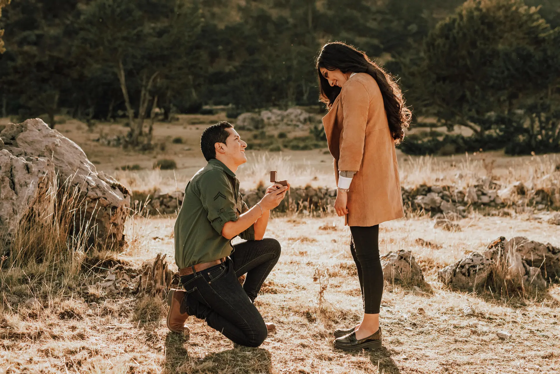 Man on one knee proposing to his girl on a barren landscape