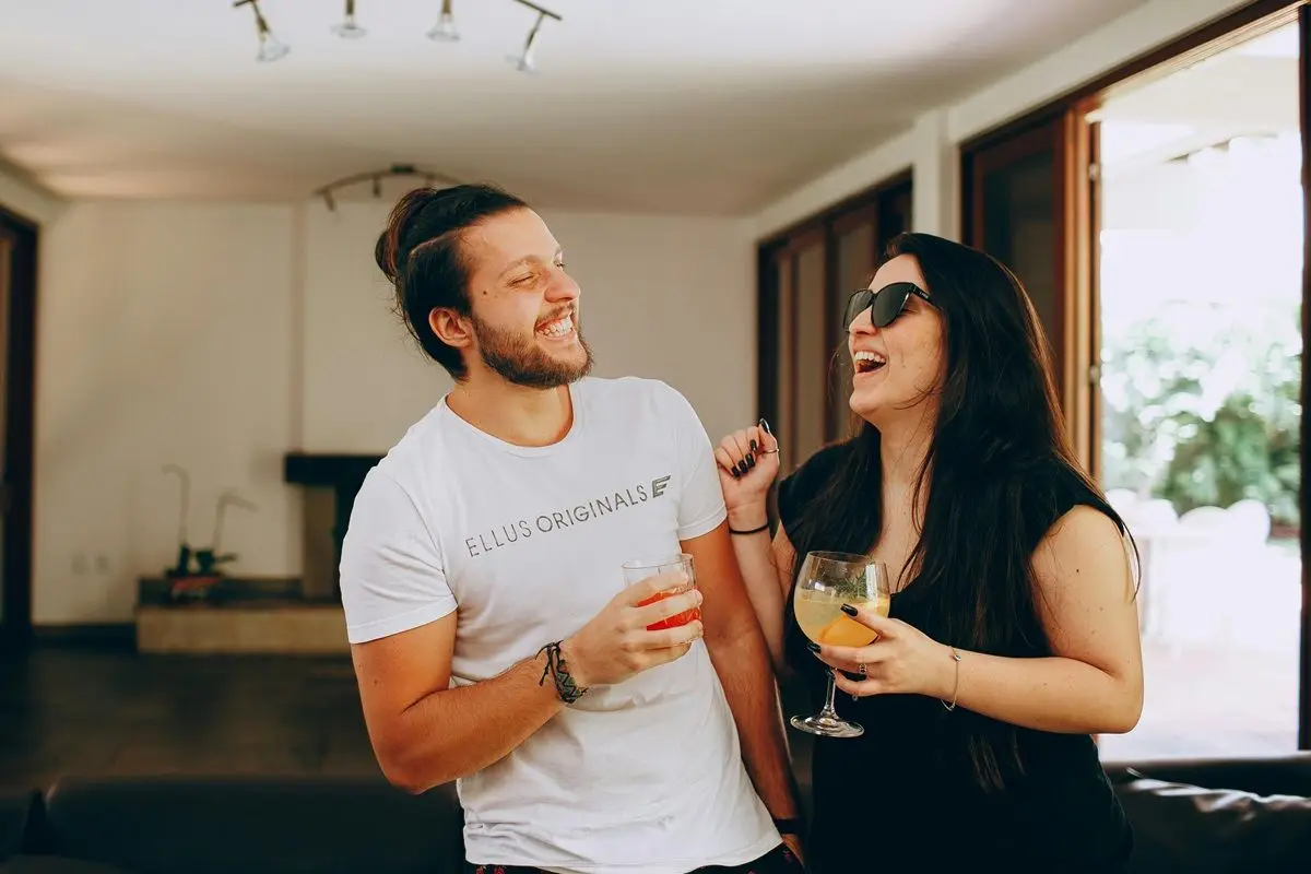 Two people have drinks in their hands and laughing.