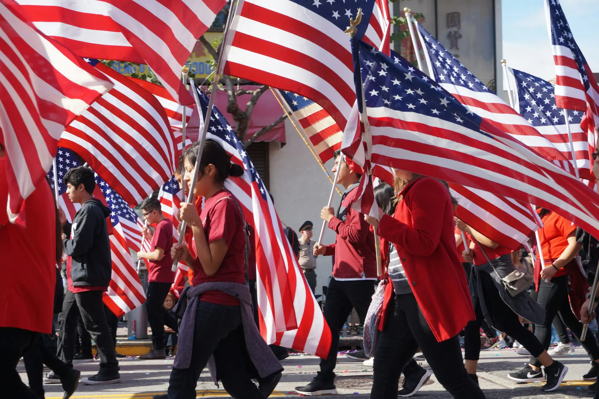 Bunch of people waving the American flag in a parade.