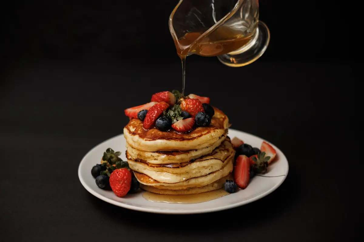 Mouthwatering stack of pancakes topped with fresh berries and drizzled with syrup, perfect breakfast for National Pancake Day.