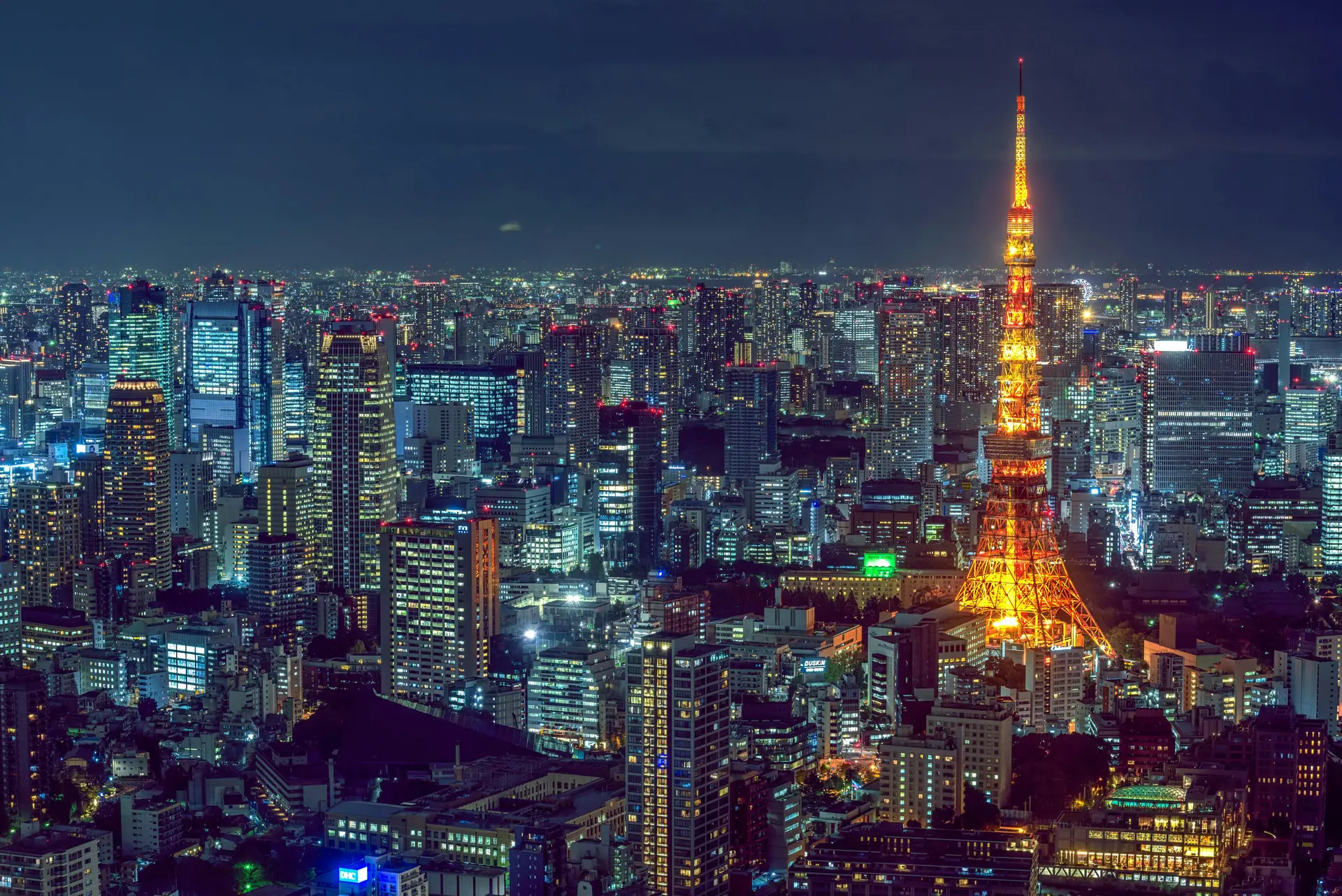 Bunch of skyscrapers in night time along with an illuminated tower in Japan.