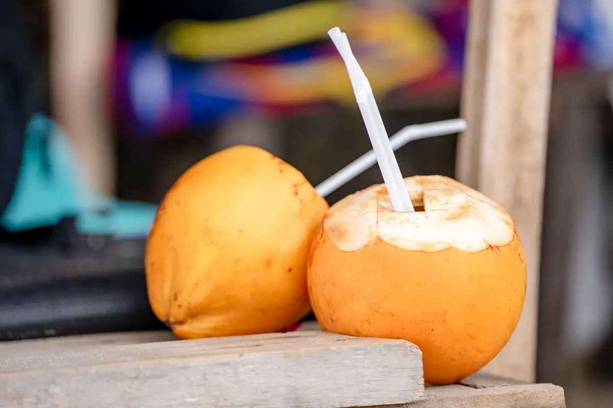 Fresh yellow coconuts with drinking straws, perfect for a tropical refreshment.
