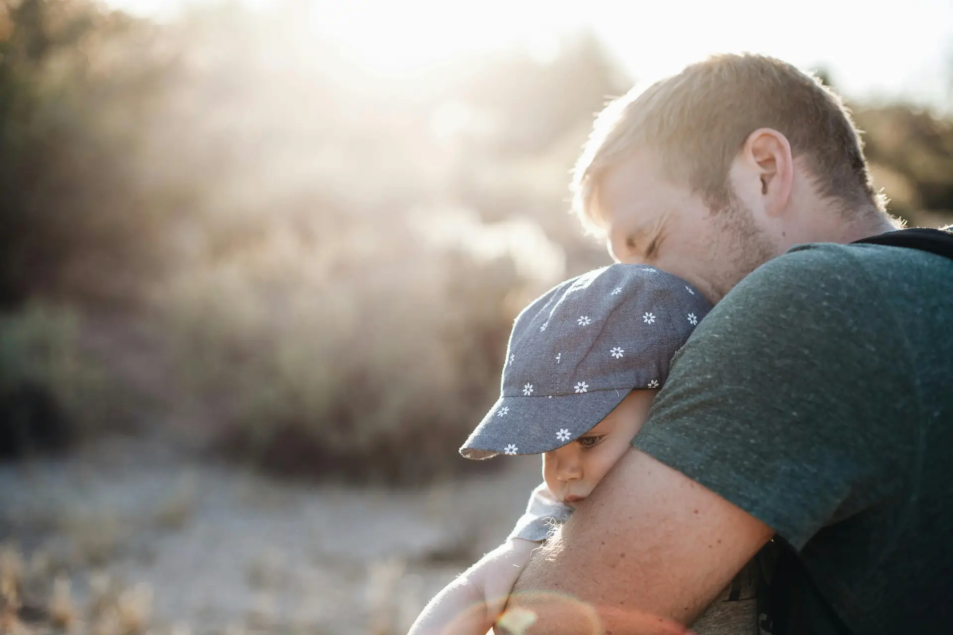 A dad hugging is baby on an afternoon.