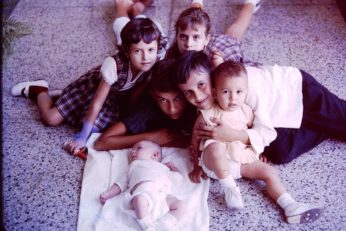 A heartwarming scene of cousins cuddled around a baby on a terrazzo floor.