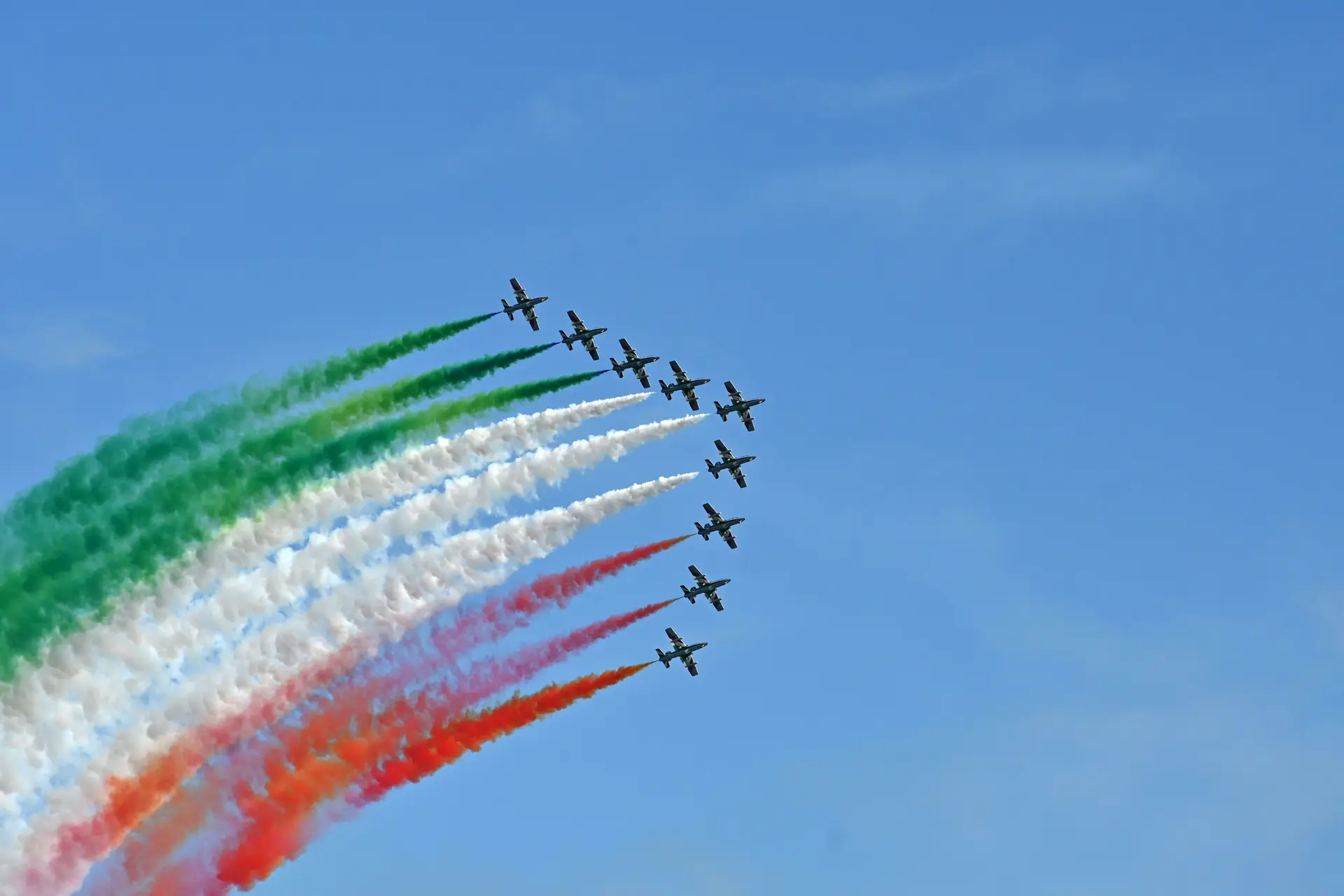A group of jets flying in formation in the sky while spewing the color of the Italian flag.