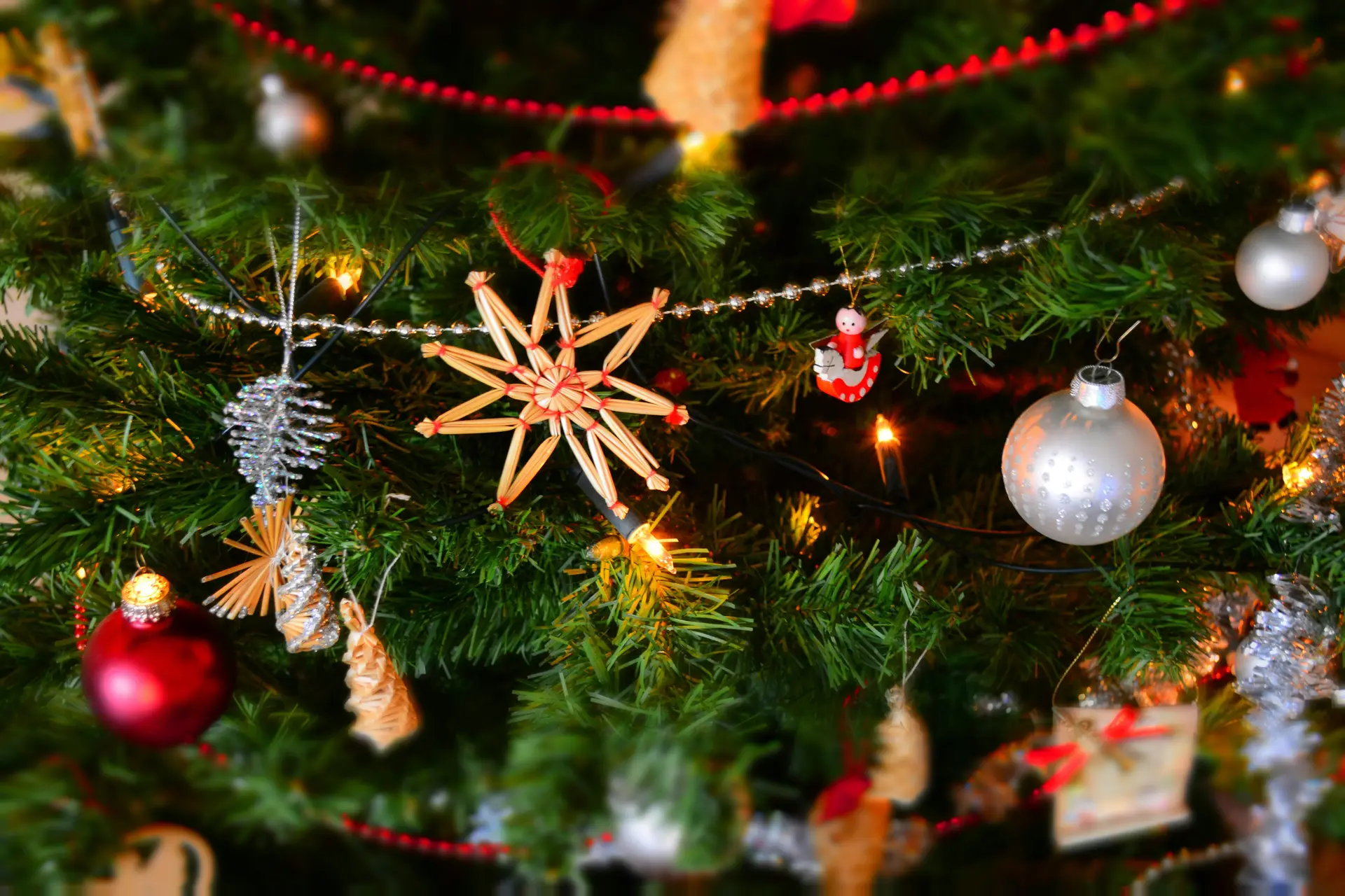 Various Christmas decorations on an evergreen tree, including lights, starts, balls, etc.