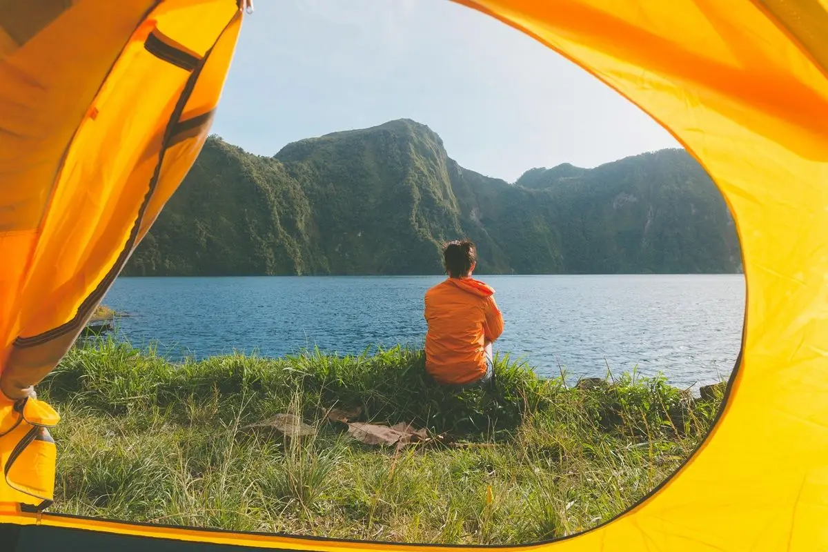 A person sitting outside of their camp looking over a body of water.