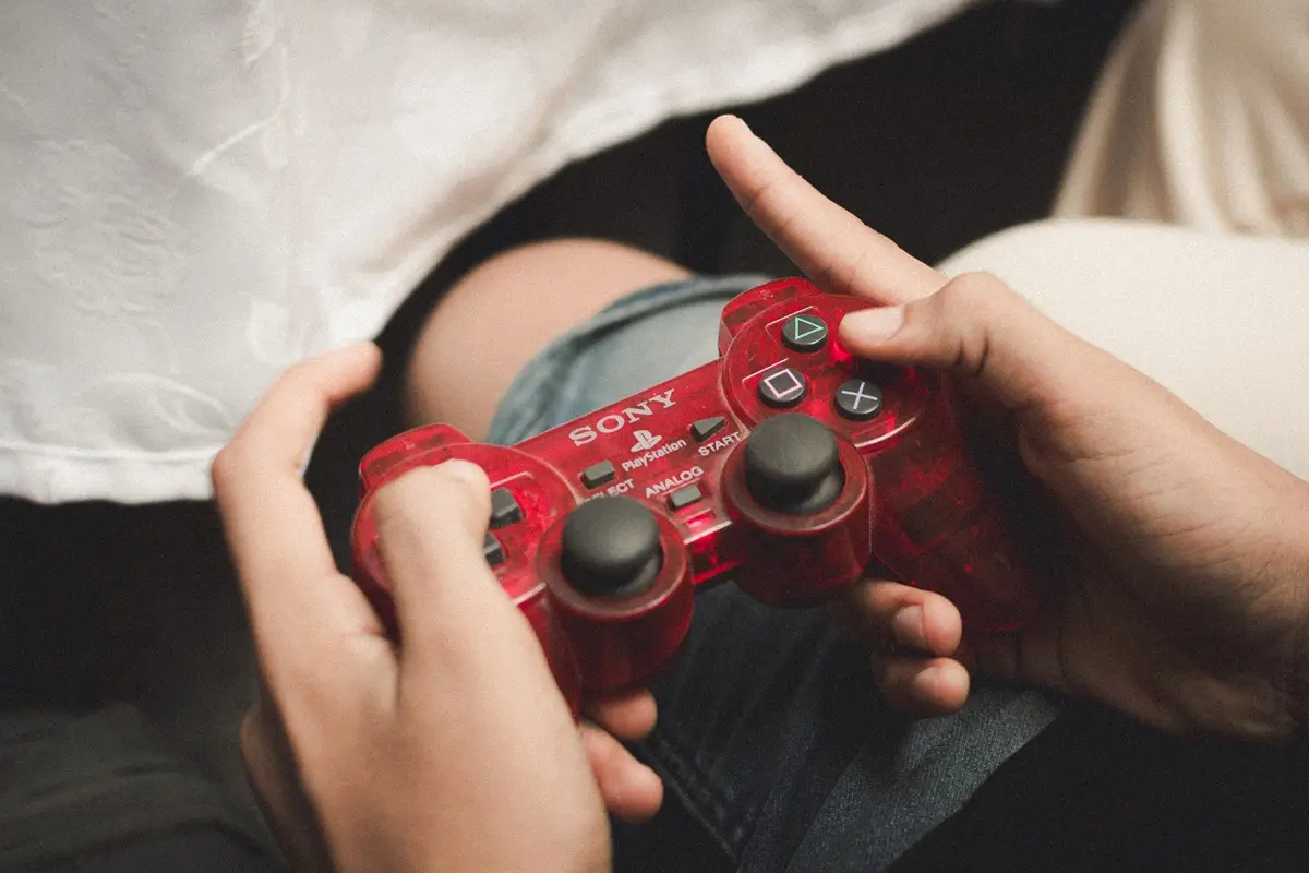 Person playing with a red PlayStation controller, evoking nostalgia for classic gaming on National Video Game Day.