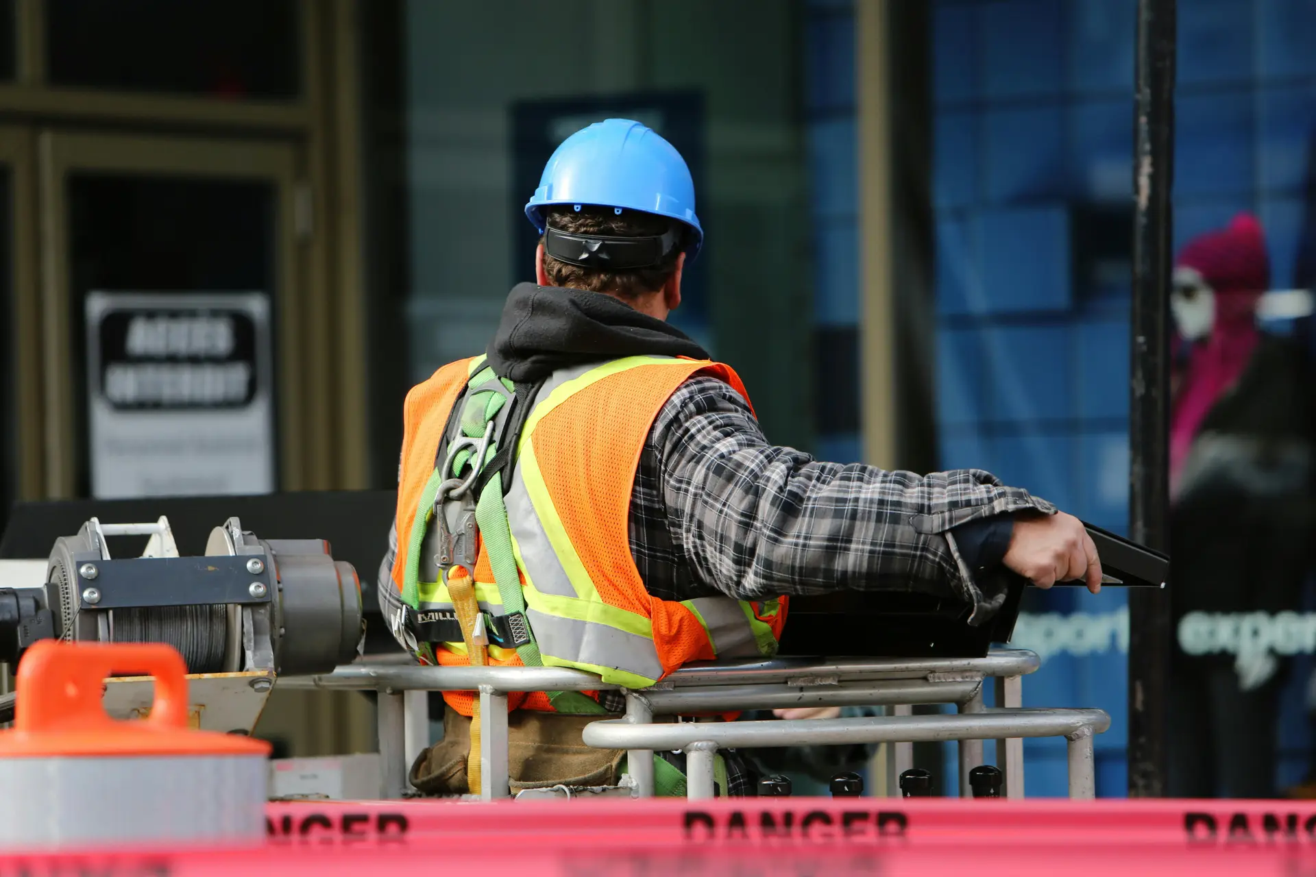 A man wearing a hard hat standing on a  crane.