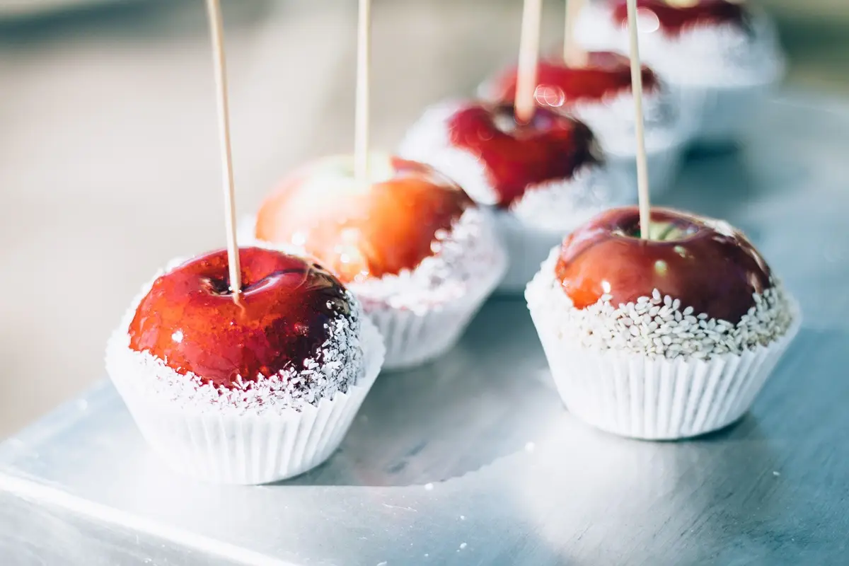 Red caramel apples with sugar coating on sticks. Perfect for sweets and confectionery themes.