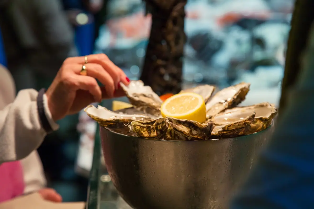 Hand reaches for fresh oysters with lemon at an Irish seafood restaurant.