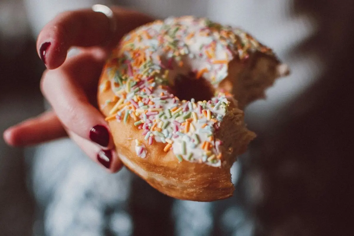 A person holding a half eaten donut.